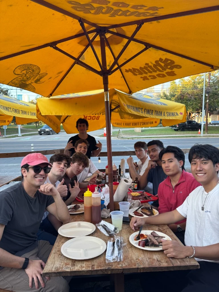 PLEC founding team sharing a meal together at an outdoor table, smiling at the camera